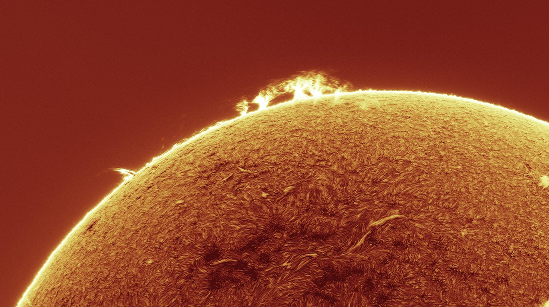 Die Sonne im H-alpha-Licht mit Protuberanzen am Rand und Filamenten auf der Sonnenscheibe